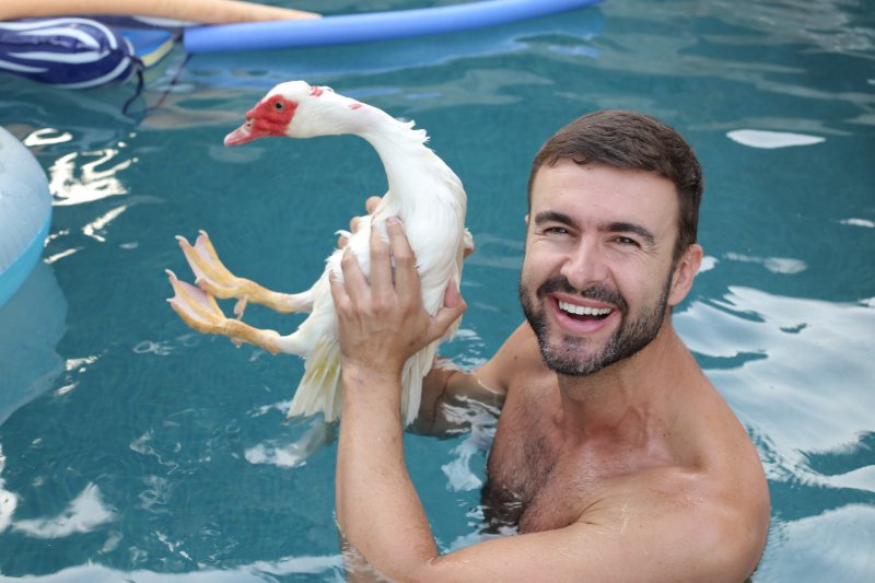 Man holding a pet duck in a swimming pool