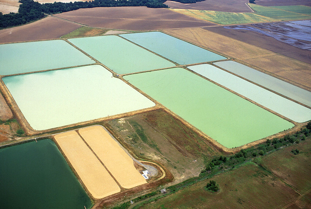 An aerial view of a pond surrounded by lush greenery, with aeration equipment installed