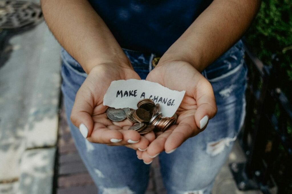 Hands with make a change note and coins for donation